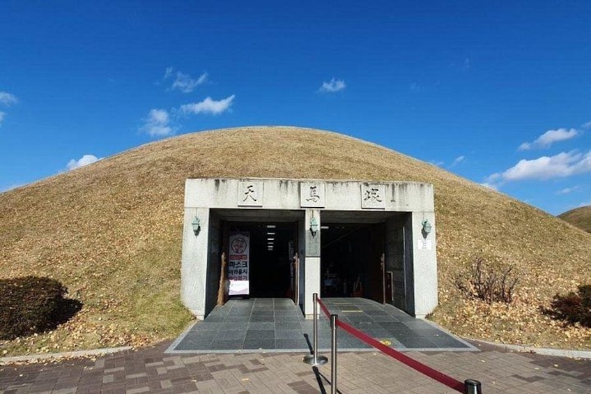 A concrete entrance with a ramp leading up to it, surrounded by a grassy hill. 3