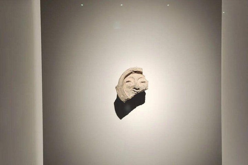 A stone sculpture with a carved face, mounted on a wall. 2