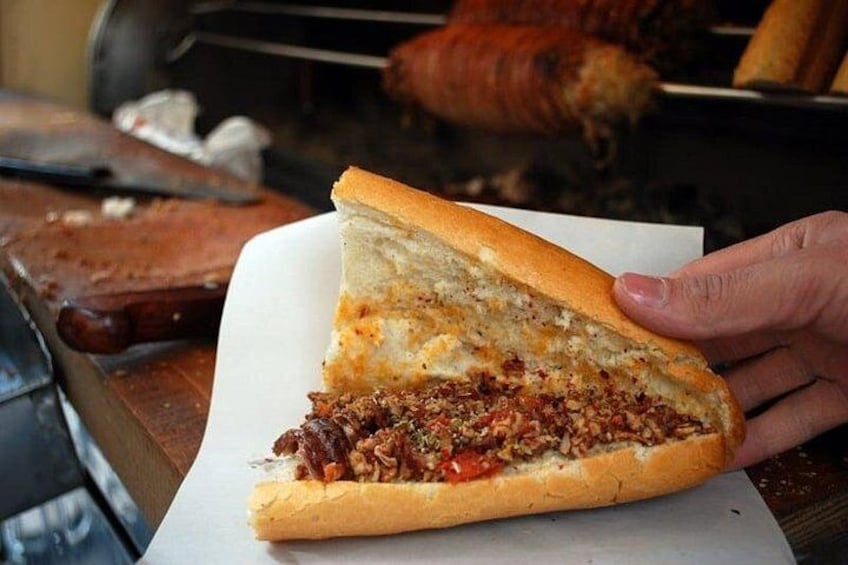 A person holding a sandwich with a visible filling of meat and vegetables. 2