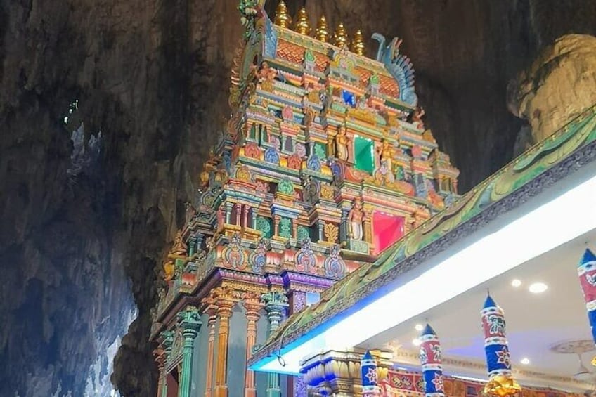 Un templo colorido con intrincados grabados y detalles dorados, ubicado frente a una pared rocosa. 5