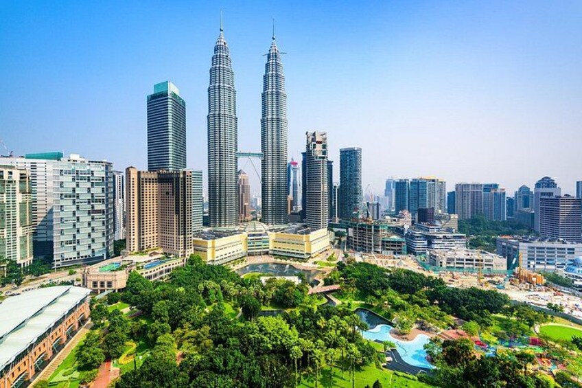 Un paisaje urbano con rascacielos modernos, incluyendo las Torres Petronas, y una extensa área verde con parque. 1