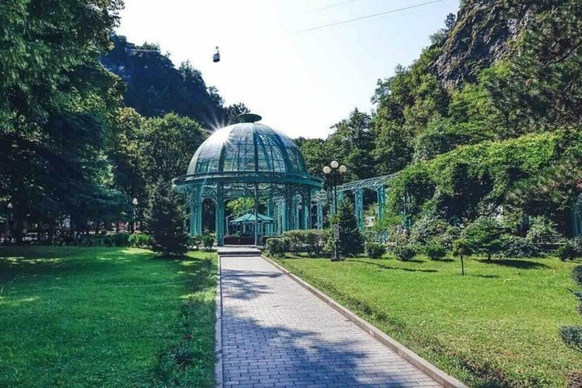A green glass-domed pavilion in a park with a paved path leading to it. 3