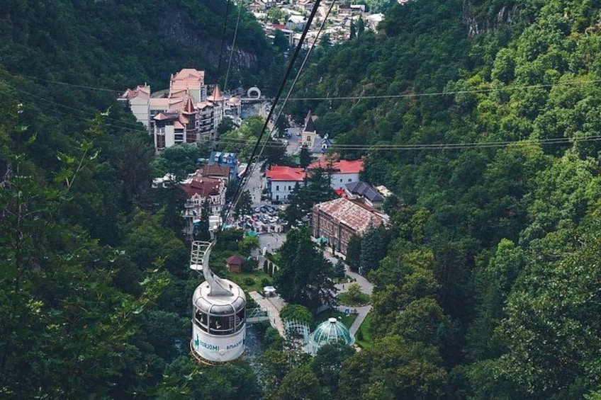 A cable car system in a mountainous area with buildings and greenery. 4