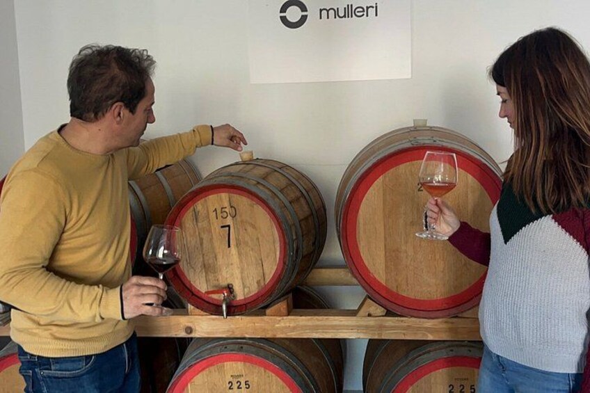Two people tasting wine at a winery with wooden barrels labeled with numbers. 2