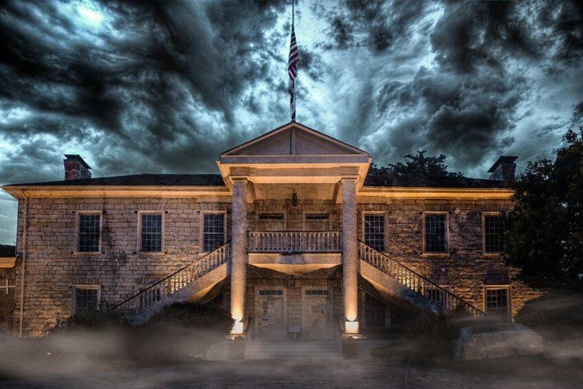 A historic building with a central staircase, columns, and a flag. 4
