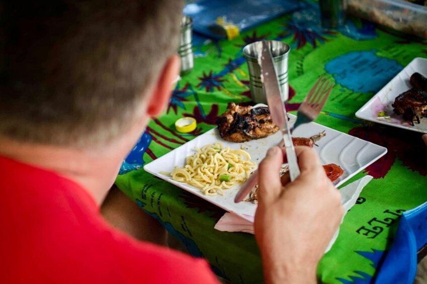 Una persona comiendo espagueti con un tenedor y un cuchillo sobre un mantel colorido. 5