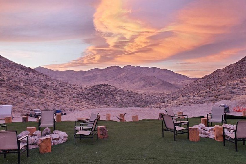 A desert landscape with mountains, a sunset, and outdoor seating. 5