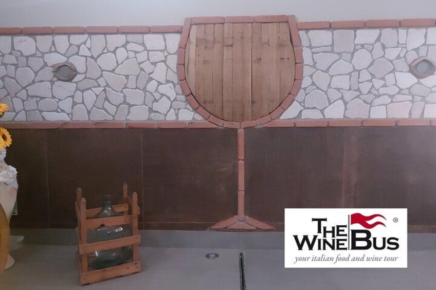 A wine tasting area with a stone wall, a wooden wine rack, and a logo for 'The Wine Bus.' 5