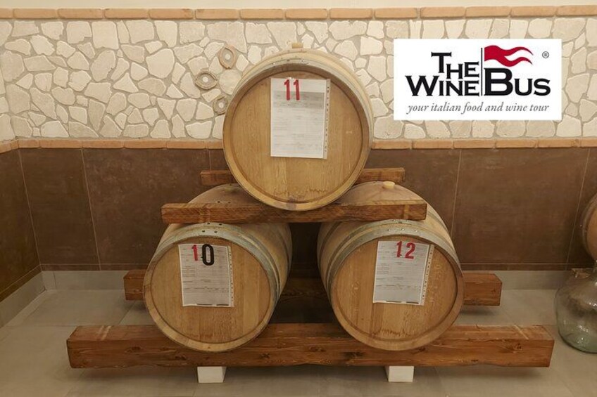 Wooden wine barrels stacked on a wooden pallet, with labels indicating their numbers. 3