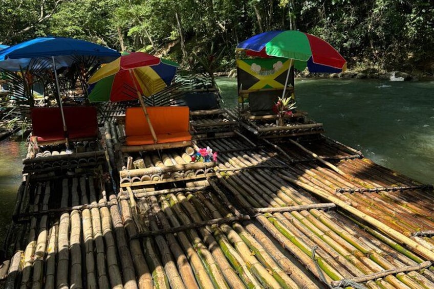 Een bamboevlot met kleurrijke parasols en een klein gebouwtje op een rivier. 4