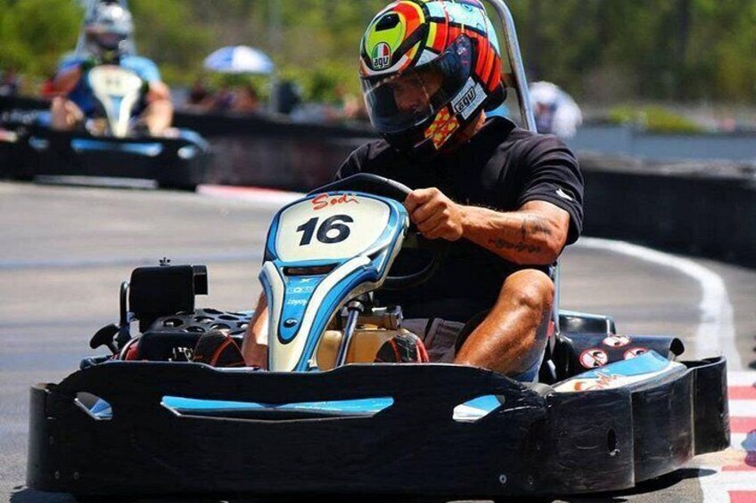 A go-kart racer in a blue and white go-kart with the number 16, on a race track. 1