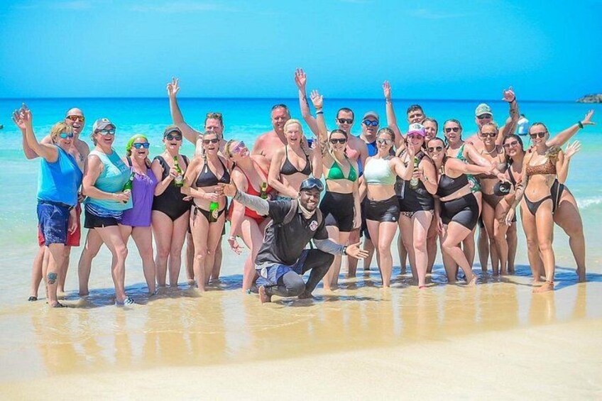 A group of people on a beach with clear blue water and a sandy shore. 2
