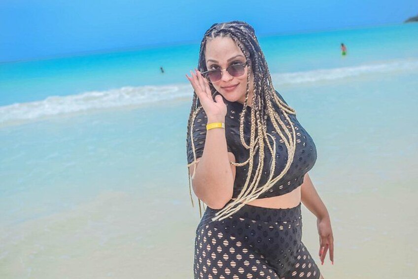 A beach with clear turquoise water and a person wearing a black outfit with a pattern. 5