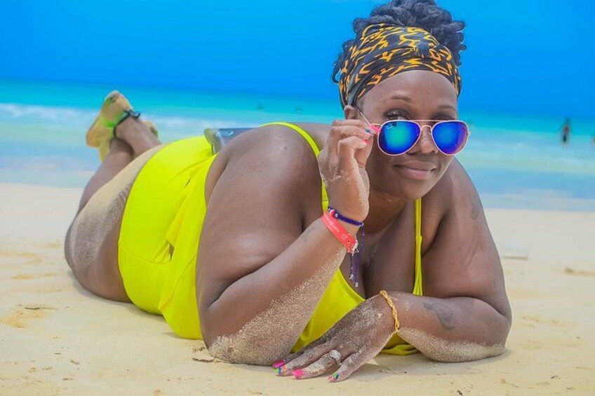 A person lying on a sandy beach with a clear blue sky in the background. 5