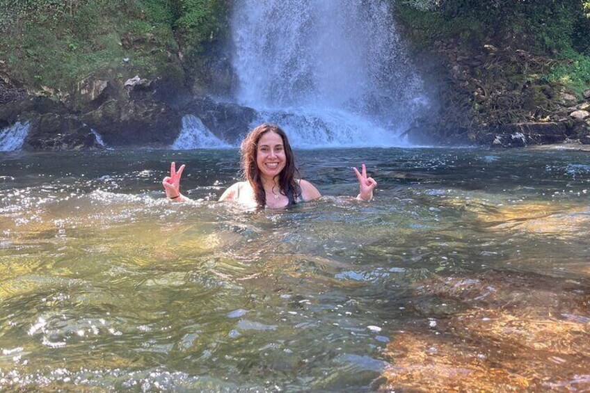 A person in clear water with a waterfall in the background. 1
