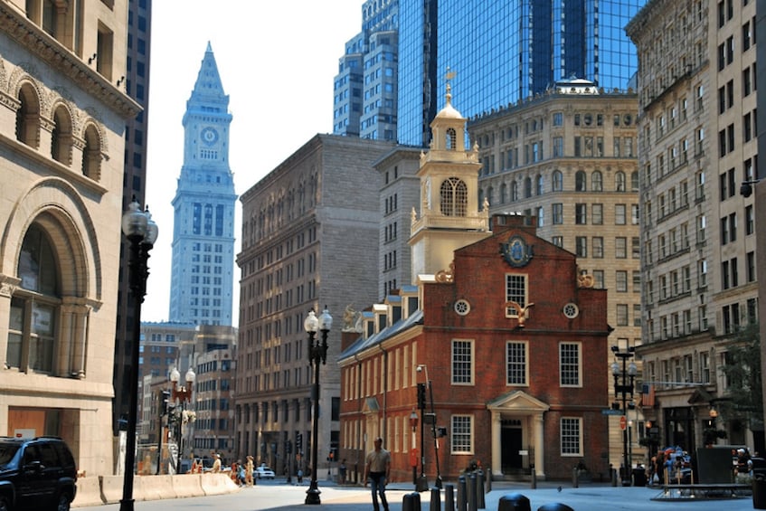 Una calle urbana con edificios históricos, una torre de reloj y rascacielos modernos. 5