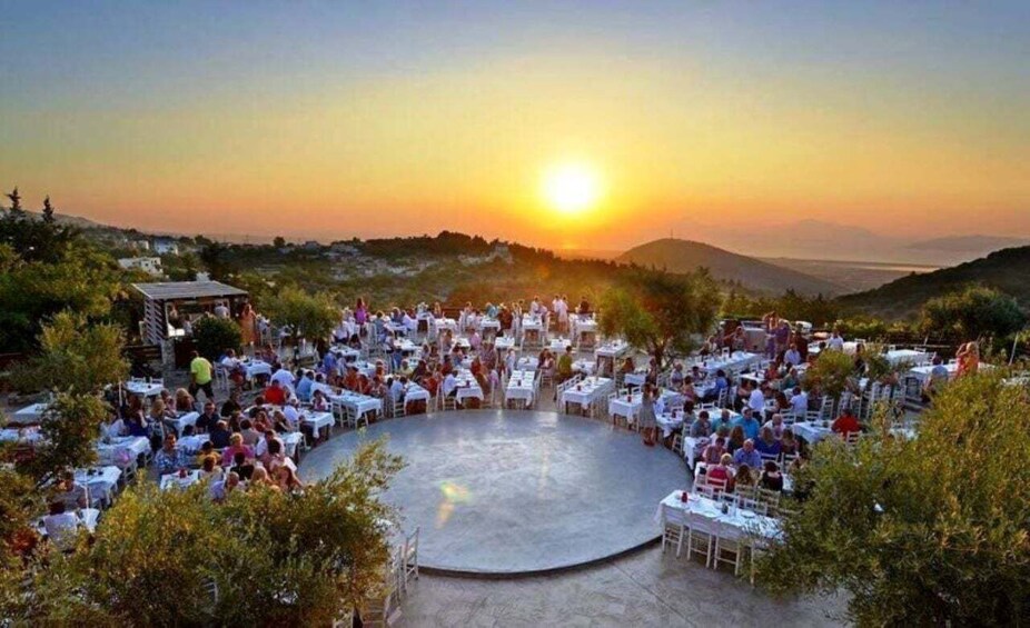 Atardecer en un evento al aire libre con escenario y mesas dispuestas para los asistentes. 1