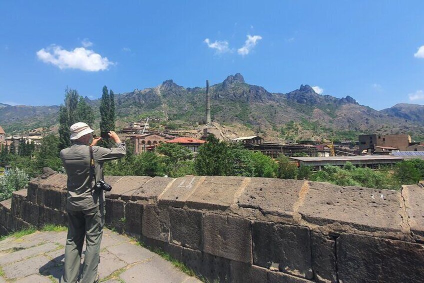 A person taking a photo of a historic site with mountains in the background. 2