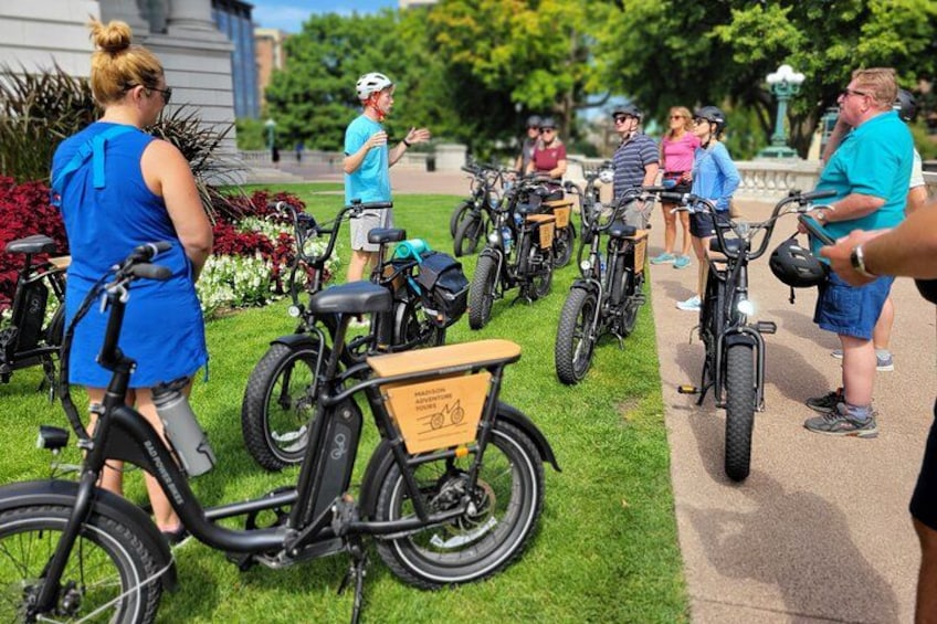 A group of people standing around bicycles in a park. 1
