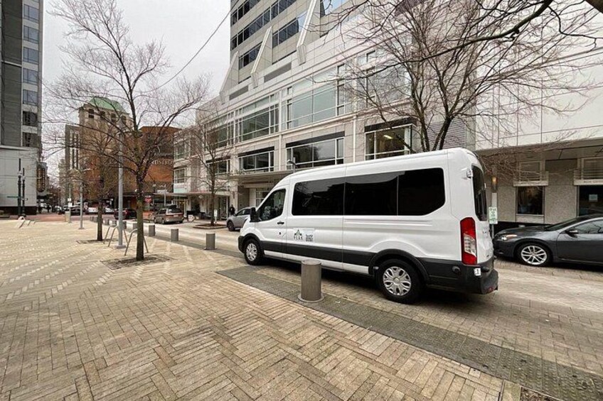 Una camioneta blanca estacionada en una acera pavimentada en una zona urbana con edificios al fondo. 4