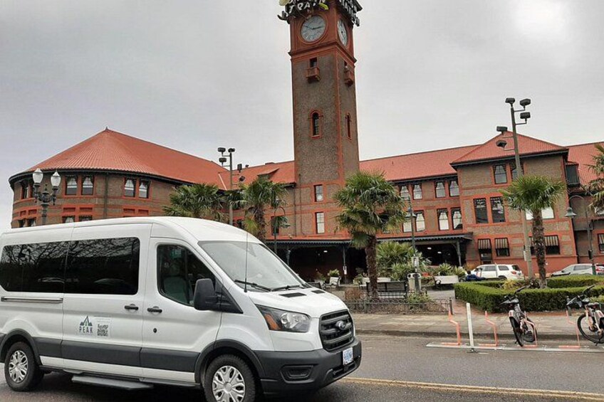 Una camioneta blanca estacionada frente a un edificio con una torre de reloj. 2