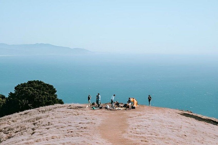 A group of people on a sandy hill overlooking a body of water with distant mountains. 2