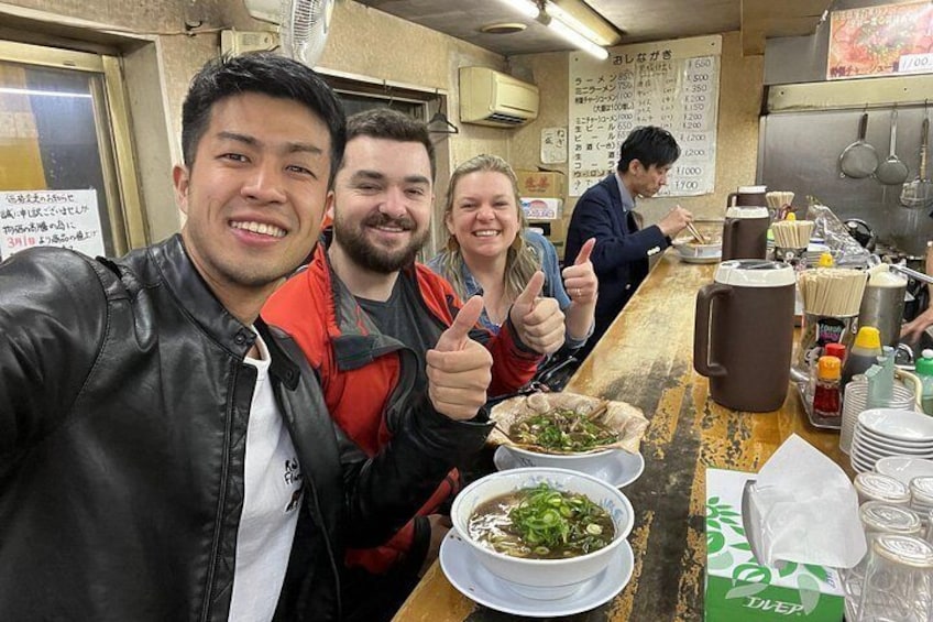 Un grupo de personas en un restaurante con tazones de comida y salsas en la barra. 3