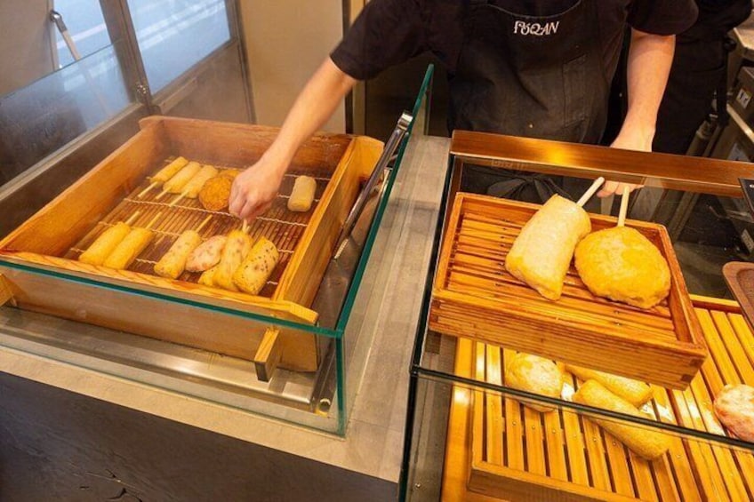 Un vendedor de comida asando salchichas tipo corn dog y sirviéndolas en una bandeja. 4