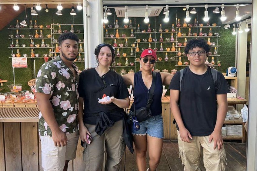 Un grupo de personas de pie frente a una tienda con estantes llenos de botellas. 5