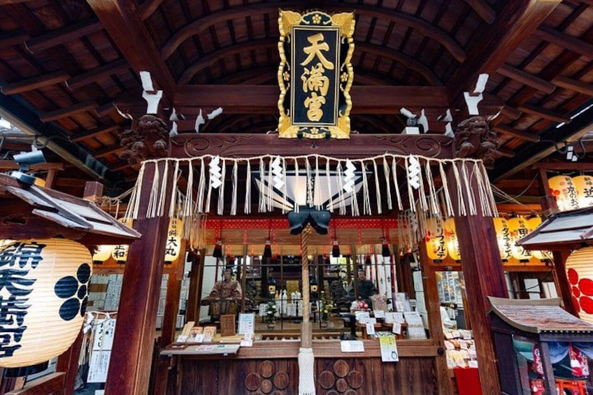 Un santuario japonés tradicional con arquitectura de madera, adornos colgantes y un letrero con caracteres japoneses. 3