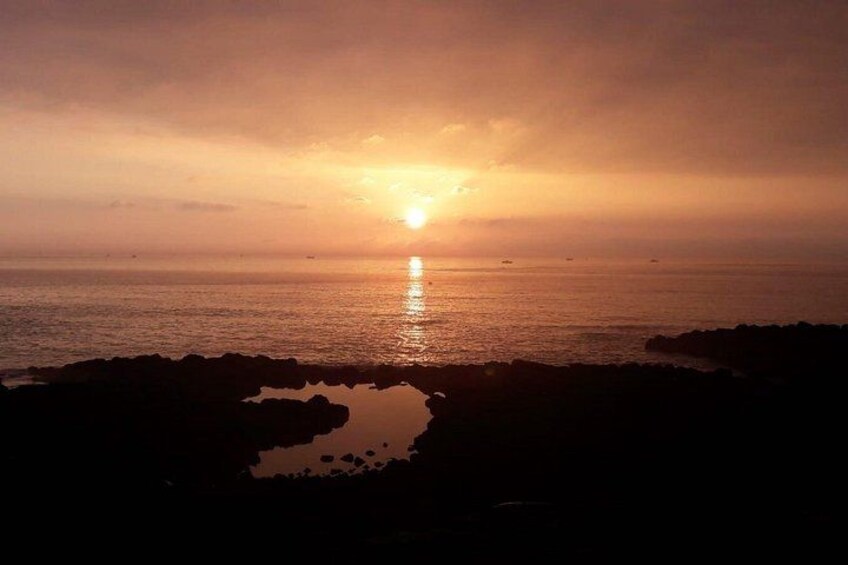 A sunset over the ocean with rocky formations in the foreground. 5