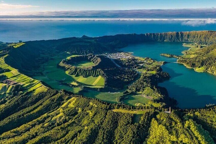 Un paisaje costero con una extensa masa de agua, campos verdes y un pequeño poblado. 1