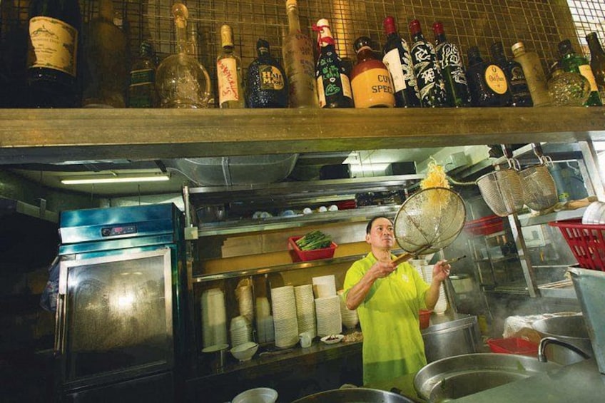 Une cuisine équipée d’ustensiles de cuisine, de bouteilles, et où une personne est en train de cuisiner. 4