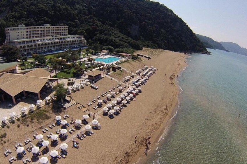 A beach with sun loungers, a swimming pool, and a hotel. 1