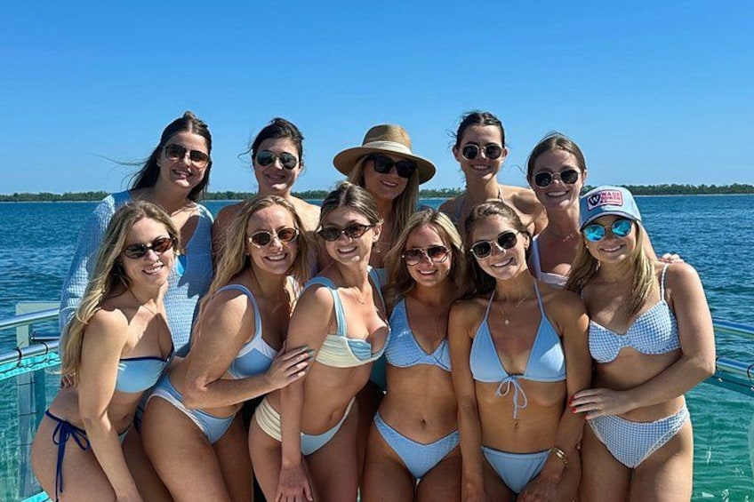 A group of people in swimsuits on a boat with a body of water and a clear sky in the background. 5