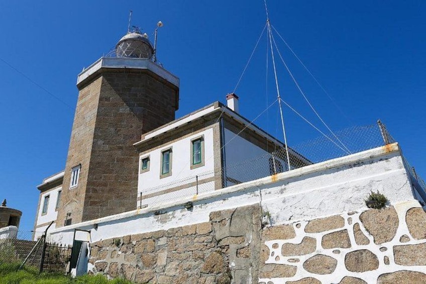 A lighthouse with a stone tower and a white building with a balcony. 3