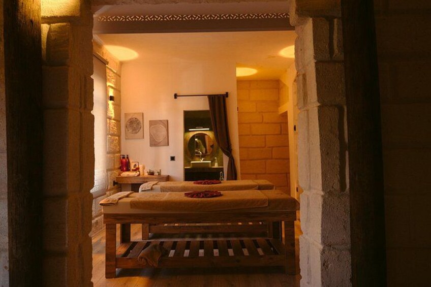A stone-walled room with a wooden bench, a table, and a mirror. 4