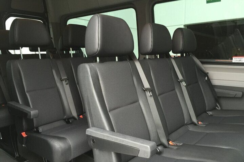 Interior de vehículo con cuatro asientos negros, cinturones de seguridad y consola central. 1