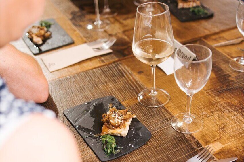 A wooden table with plates of food, wine glasses, and a menu. 3