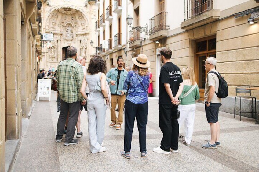A group of people standing on a city street, facing a historic building with intricate architecture. 2