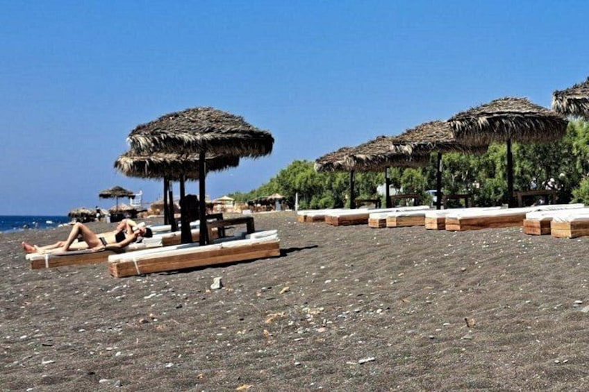 A beach with thatched umbrellas, wooden loungers, and a clear sky. 4