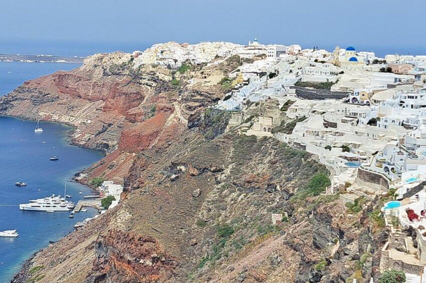 Une ville côtière aux bâtiments blancs, avec une falaise rocheuse et des bateaux sur l’eau. 2