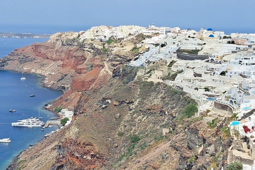 A coastal town with white buildings, a rocky hillside, and boats in the water. 3