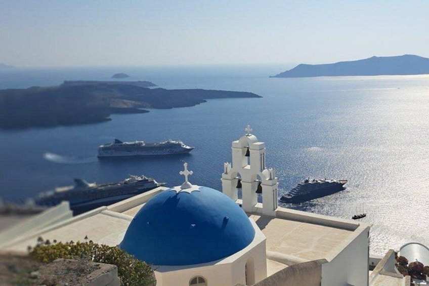 A coastal view with a blue dome, white church, and ships on the water. 2