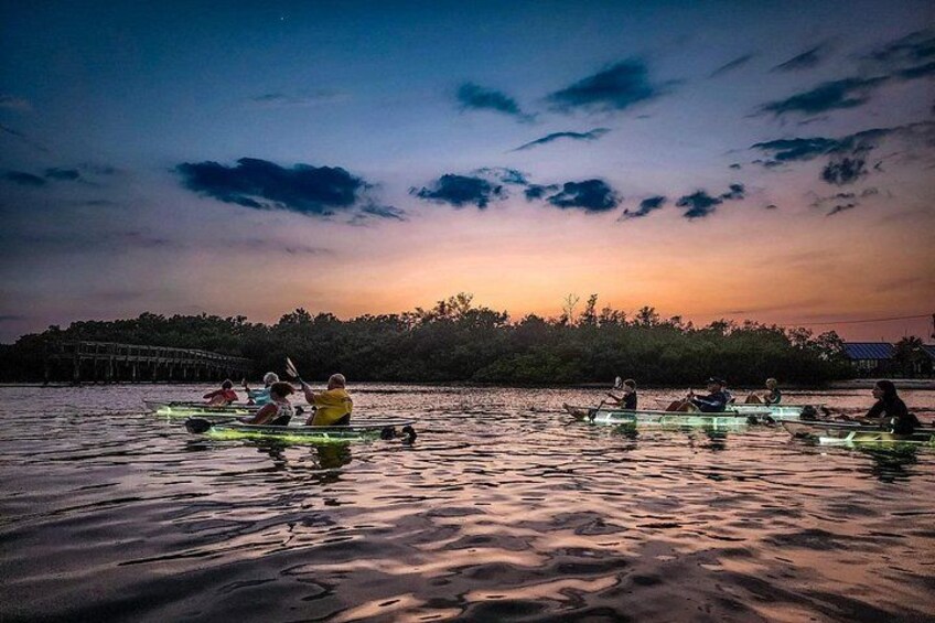 People rowing canoes on a calm body of water during sunset. 2