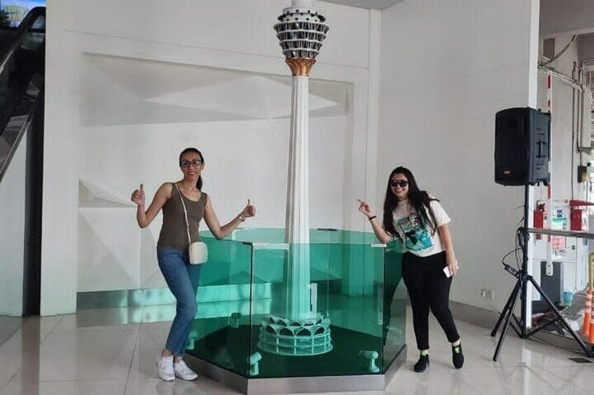 Two people standing near a glass display case with a tall, cylindrical object in the center. 2