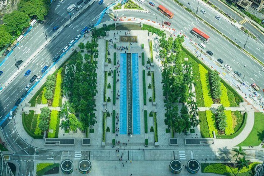 Una vista aerea di un incrocio cittadino con diverse strade, una piazza centrale con fontana e aree verdi circostanti. 2