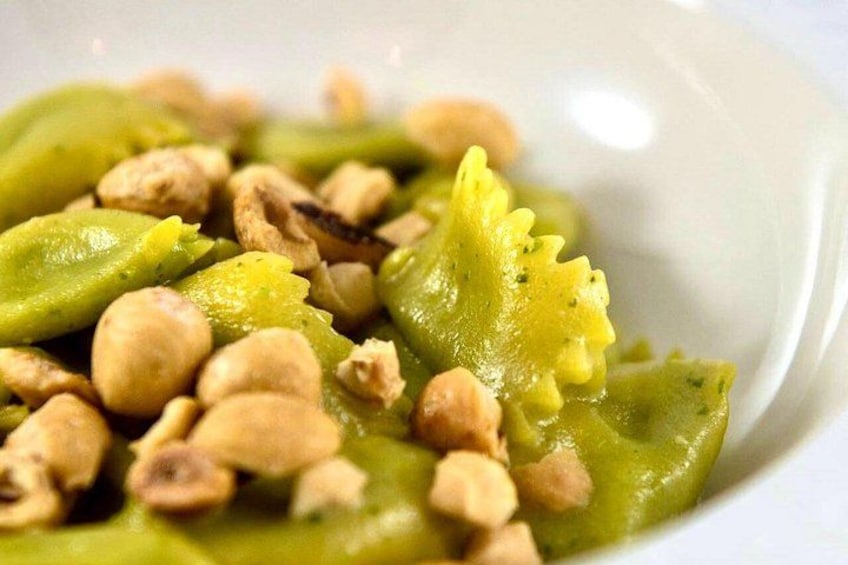 A dish with green pasta and cashew nuts. 1