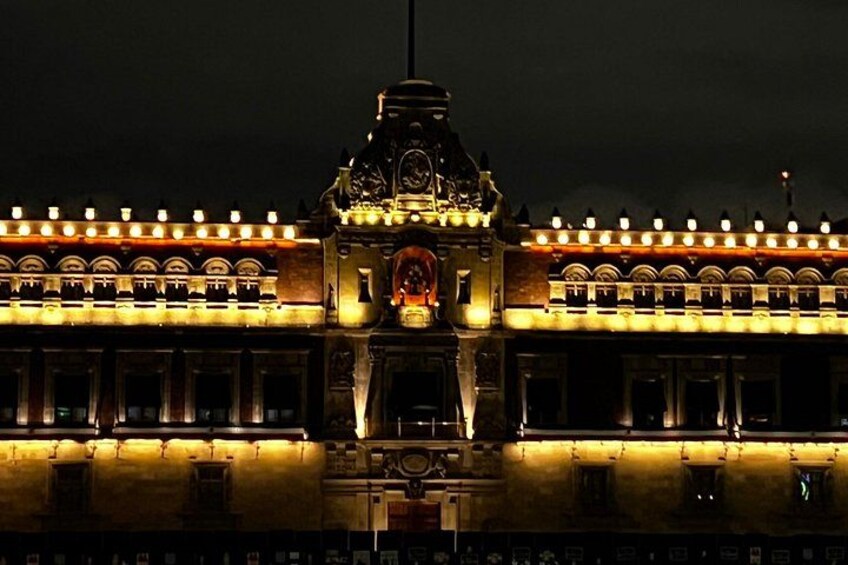 A brightly lit building with a clock tower and arched windows. 3