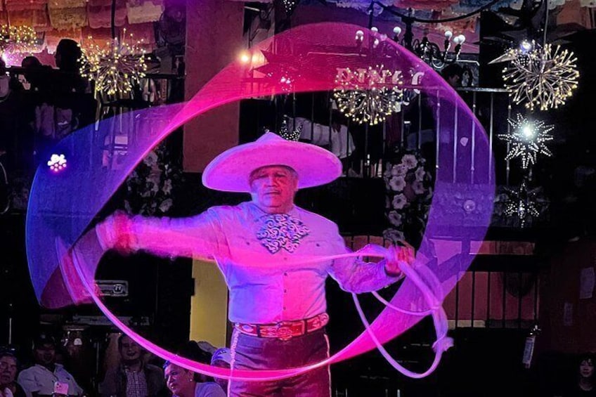 A performer with a large sombrero and a sash, holding a hula hoop. 1